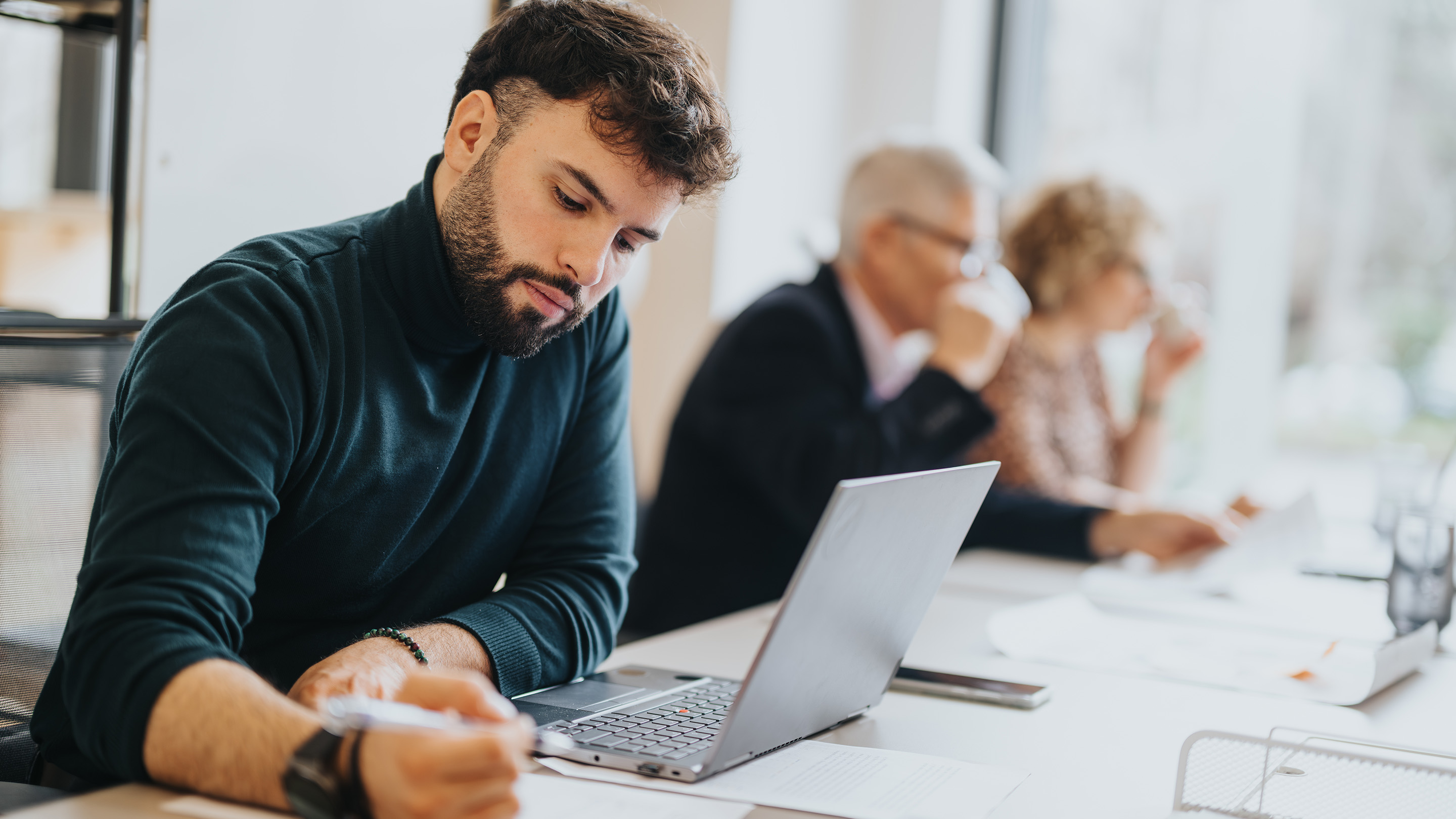 Man working on his laptop in a busy office