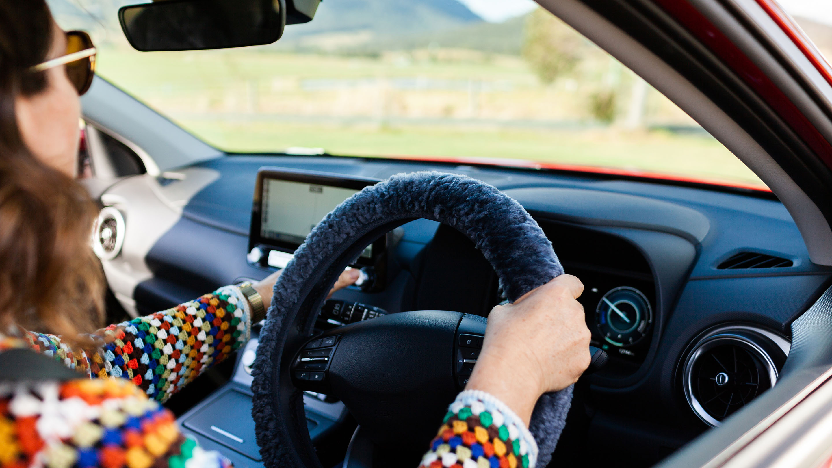 GPS navigation system in electric vehicle with a woman's hand at the wheel