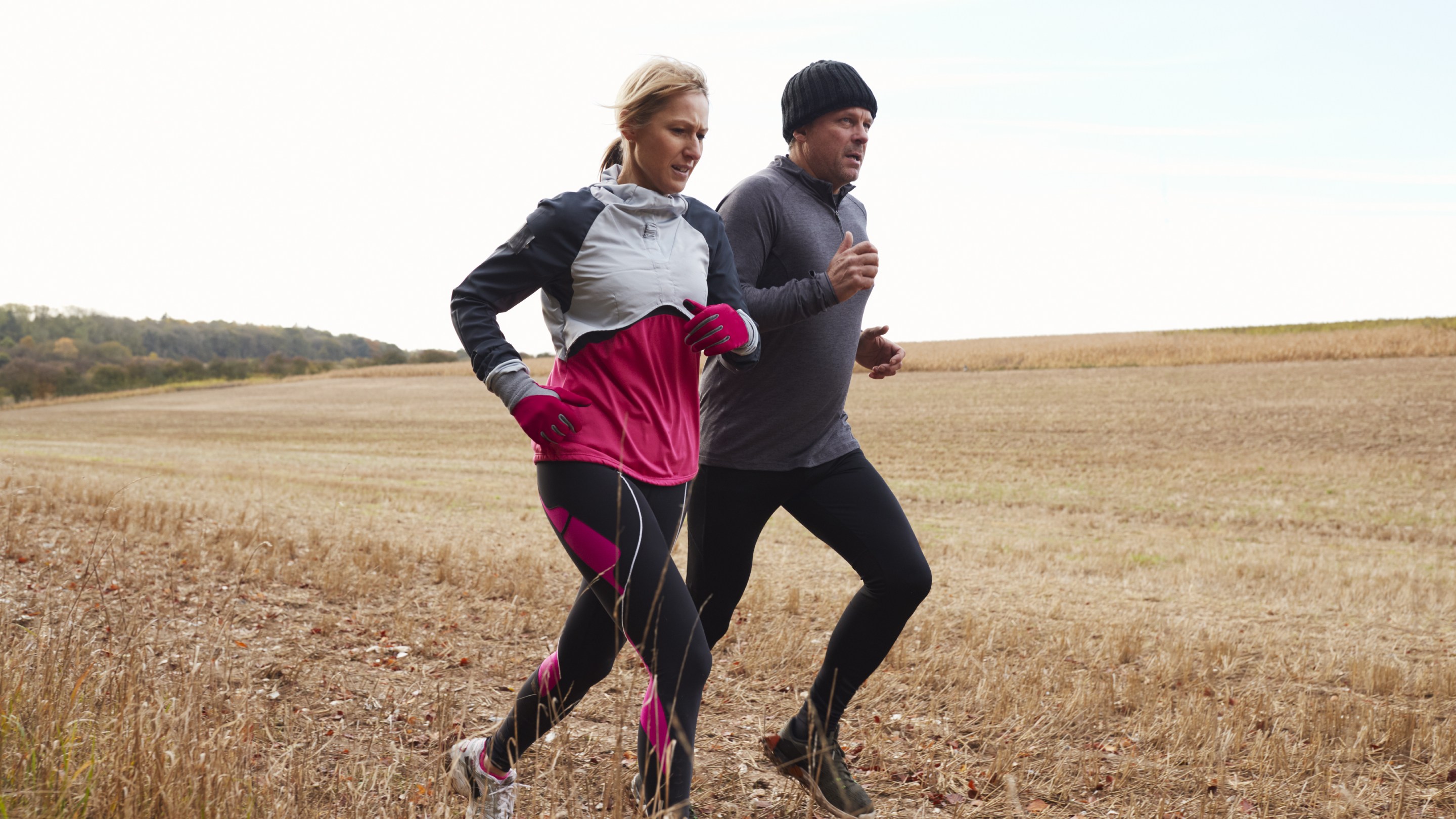 Adult couple running around field together