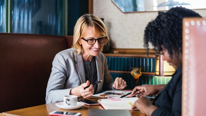 An image of two women working together at a desk