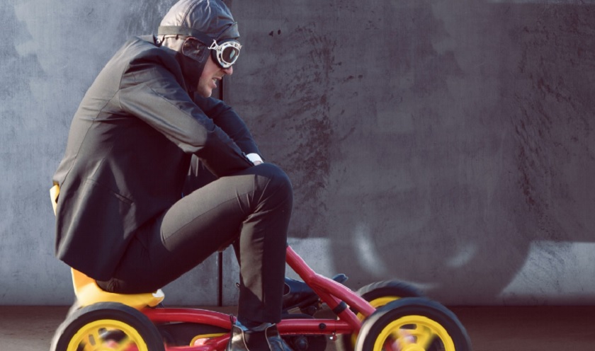 Image of a man riding a toy car