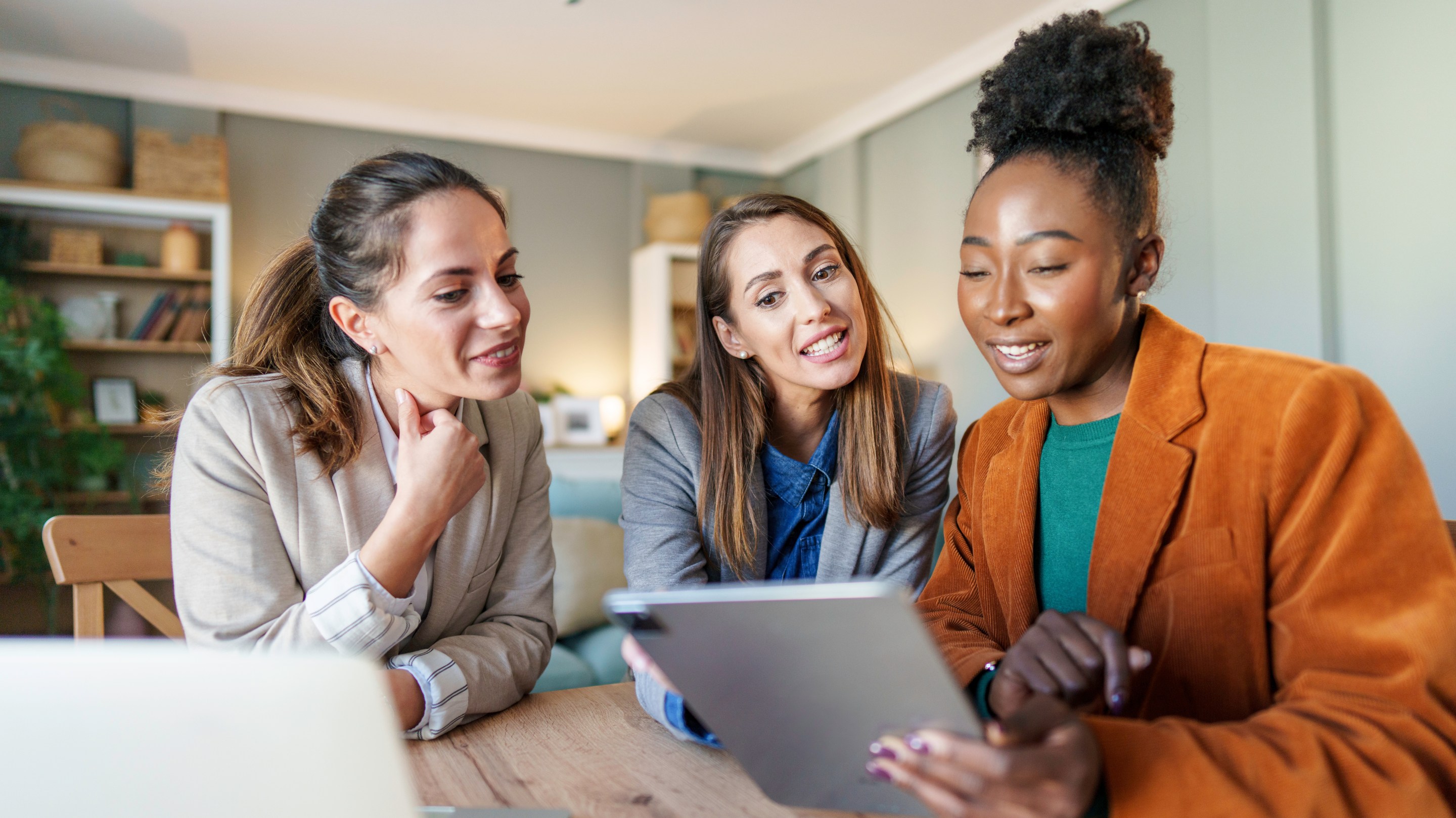 A group of female colleagues discussing work using a tablet