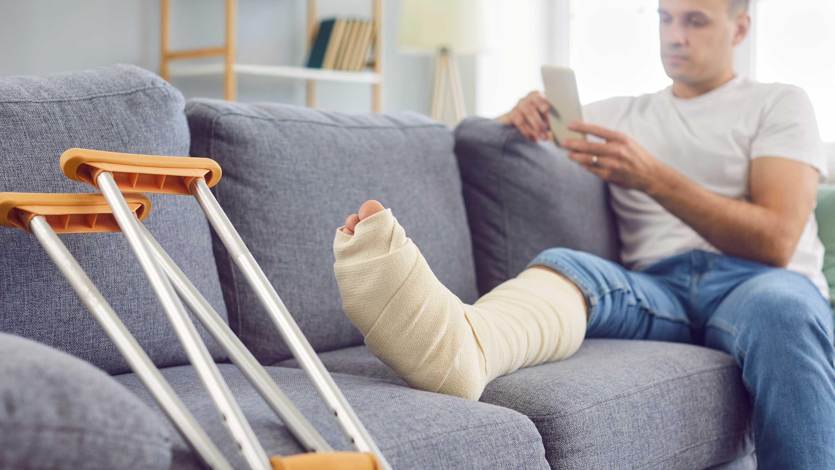 A man in a foot cast with his leg up on the sofa