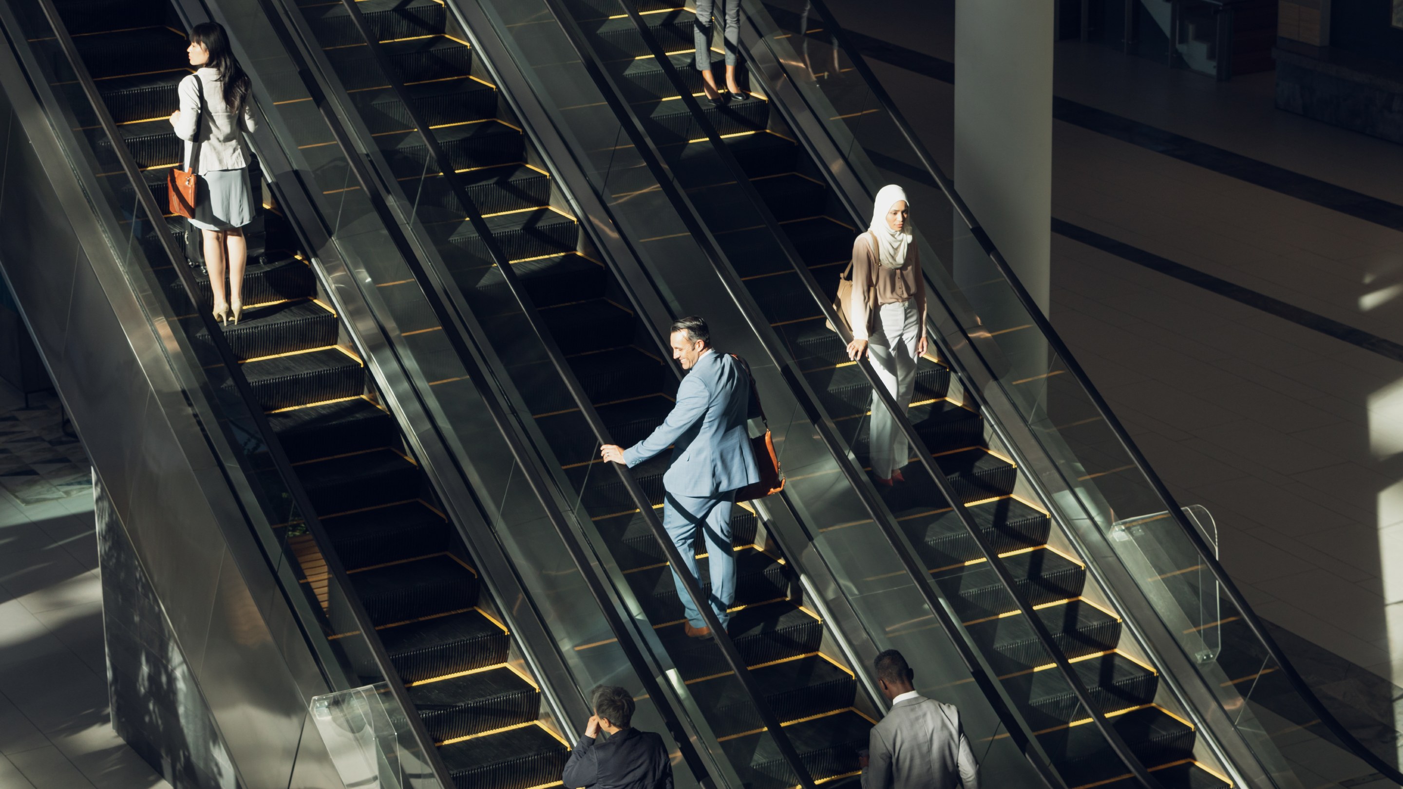 Business people using escalators in modern office