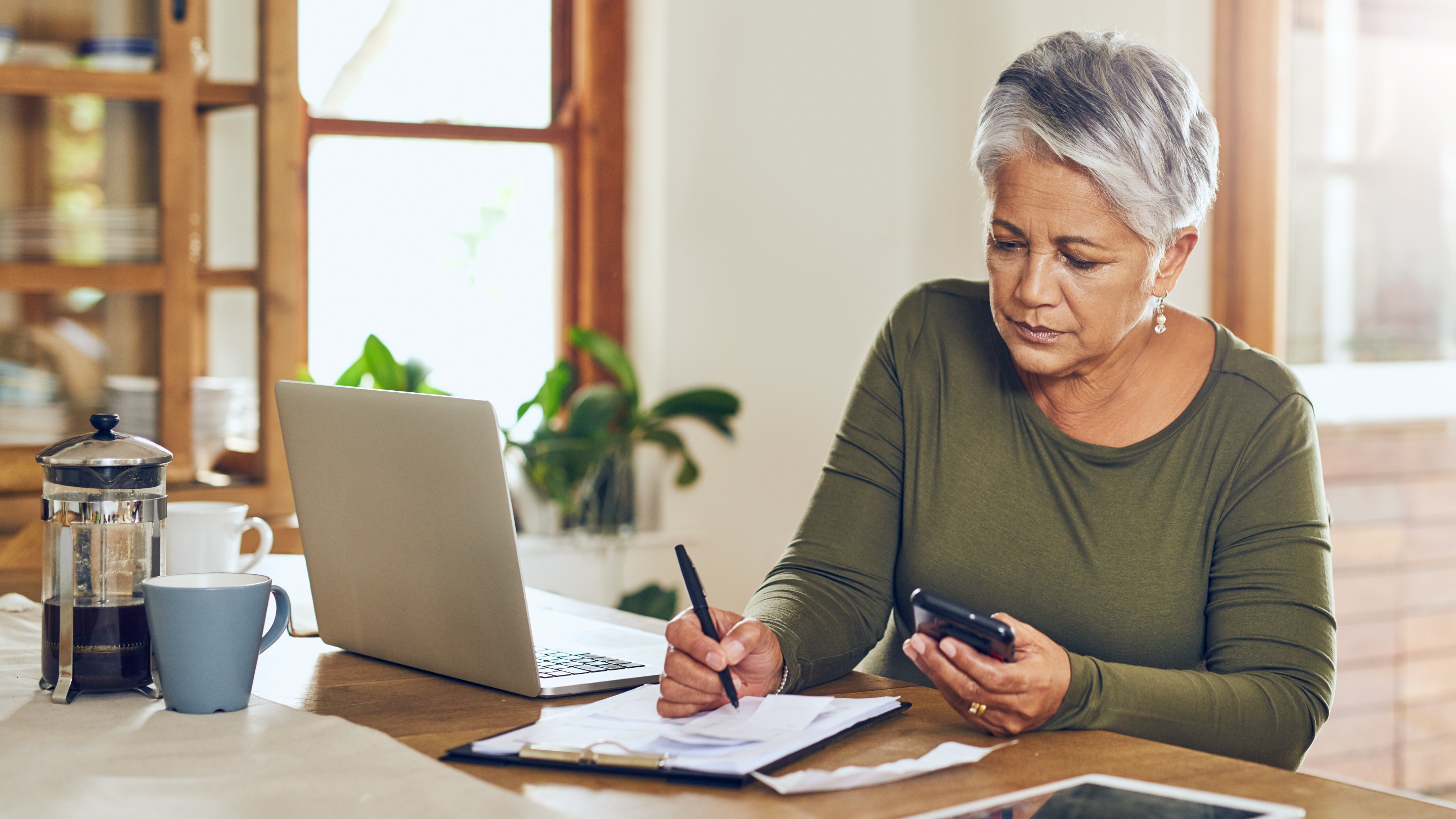 Woman at home looking at paperwork and her phone