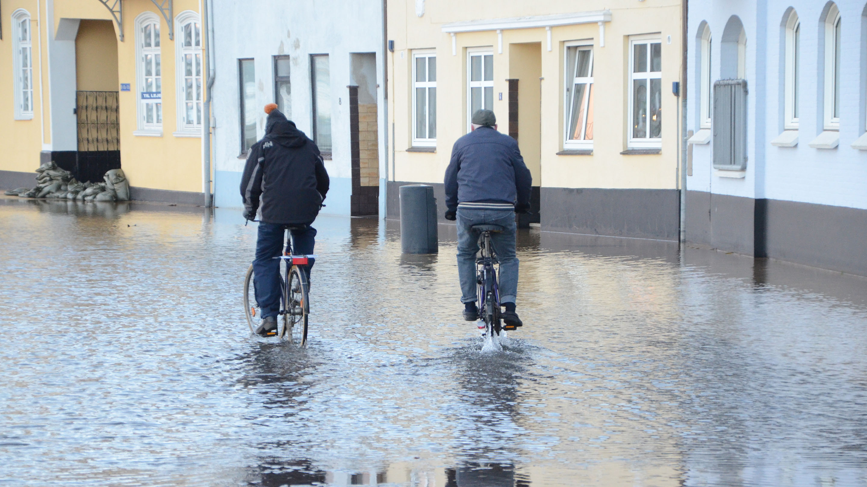 Two cyclists on road with storm surge water