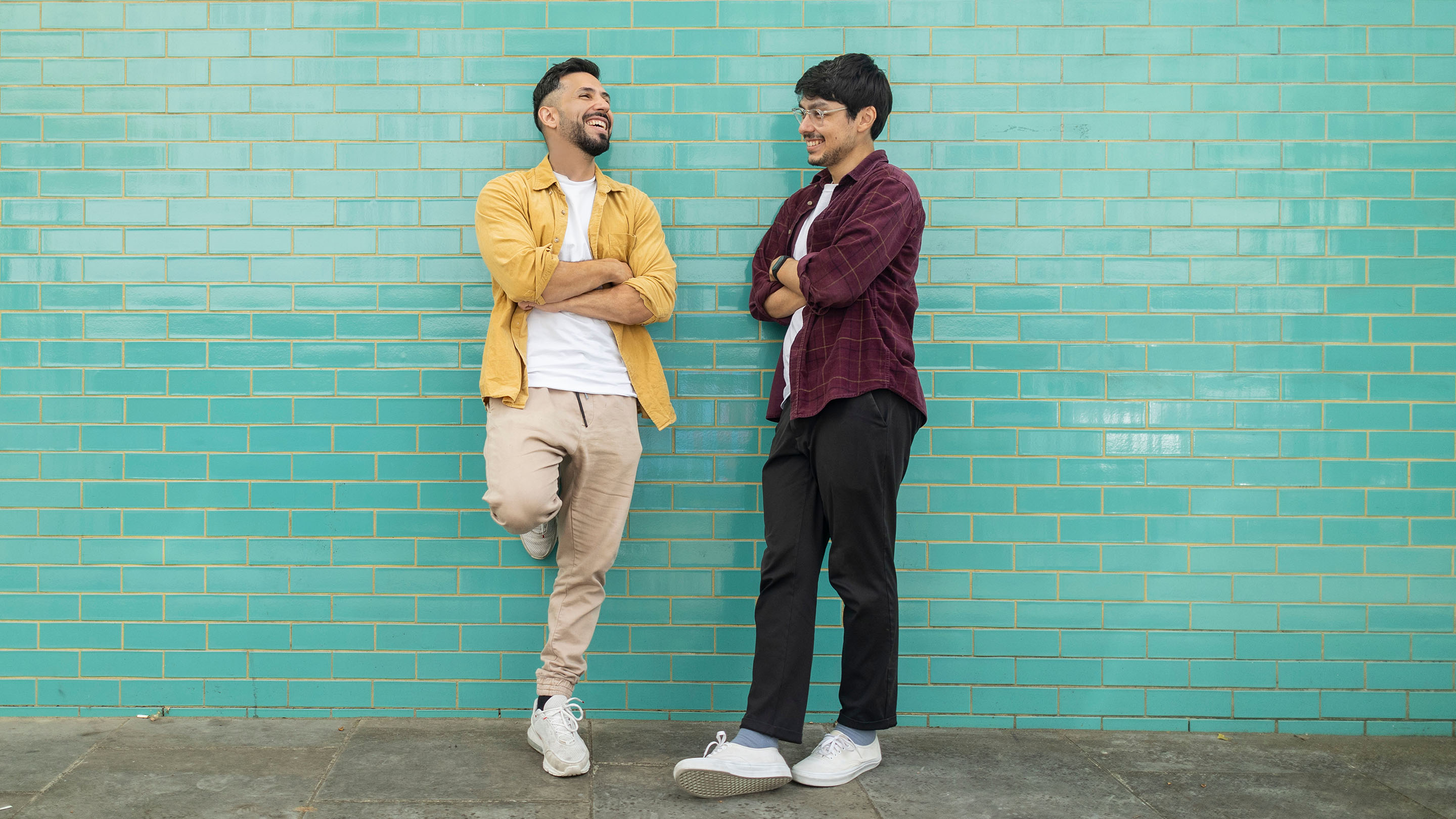 Two men talking on the street on blue wall background