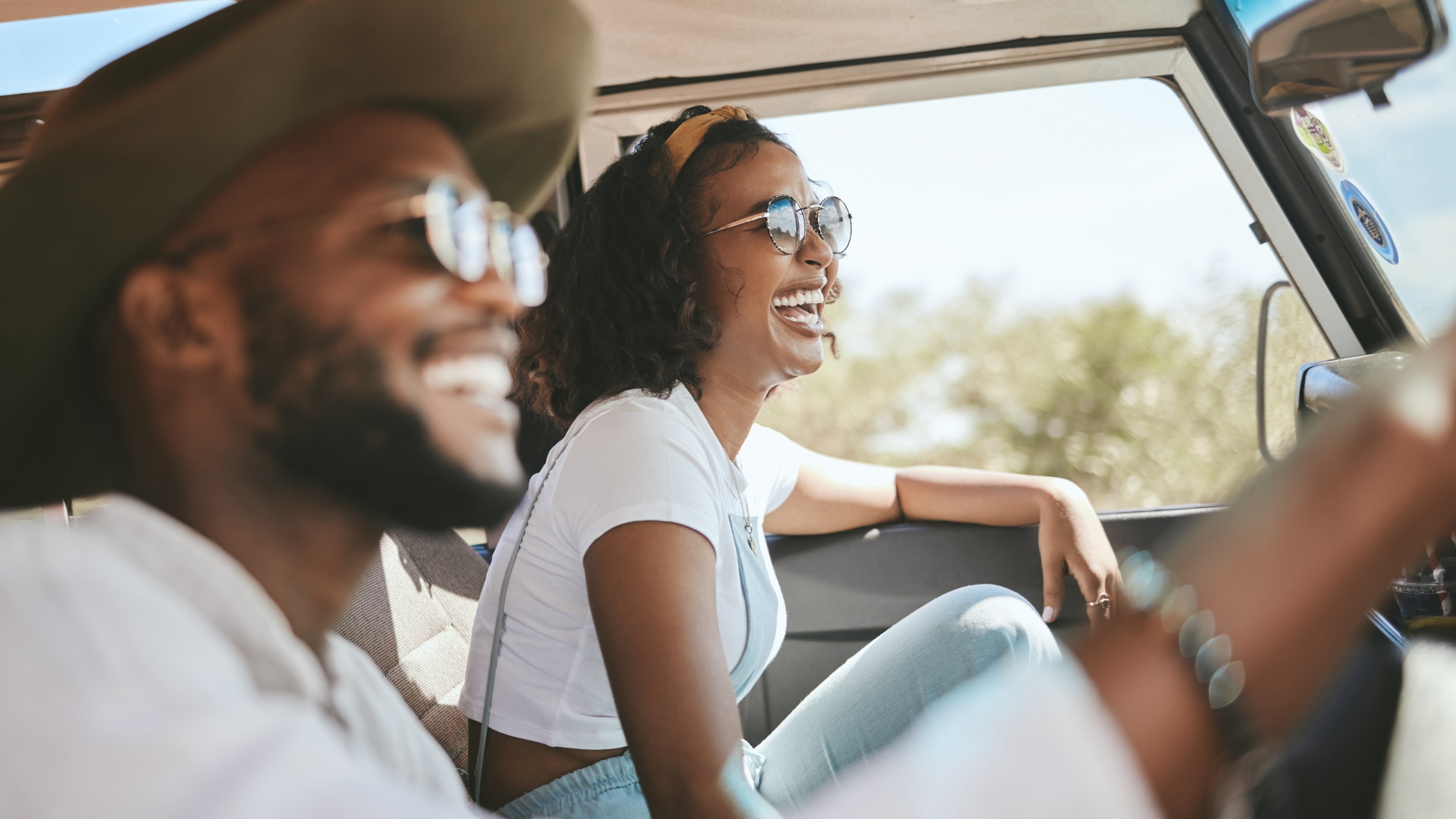 Two people smiling in their car on a road trip holiday