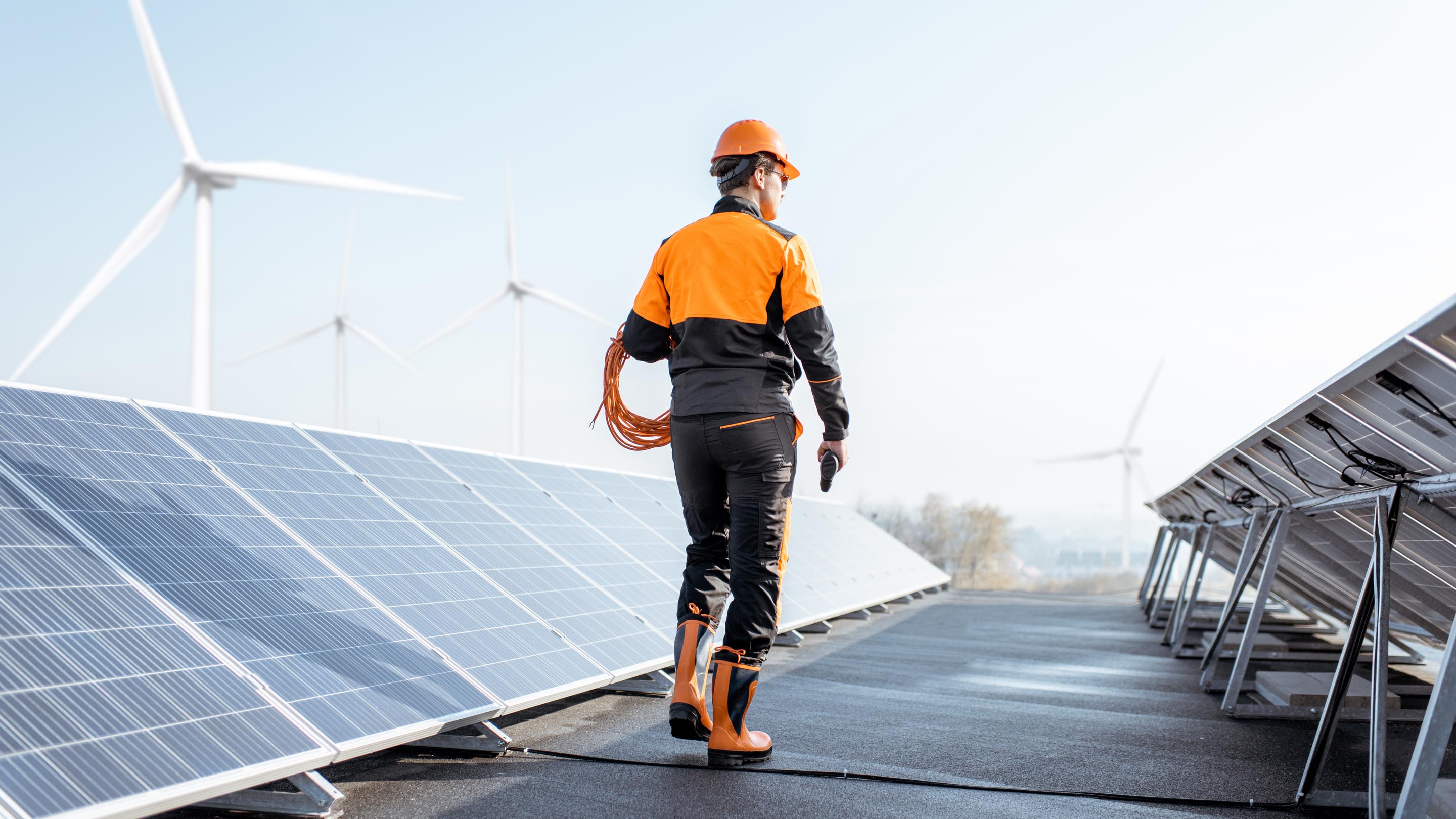 Worker in protective clothing walking past solar panels