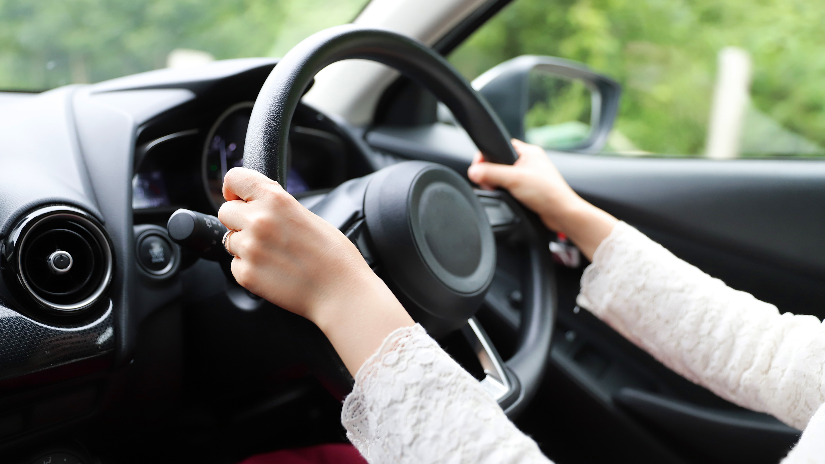 Woman with hands on car steering wheel