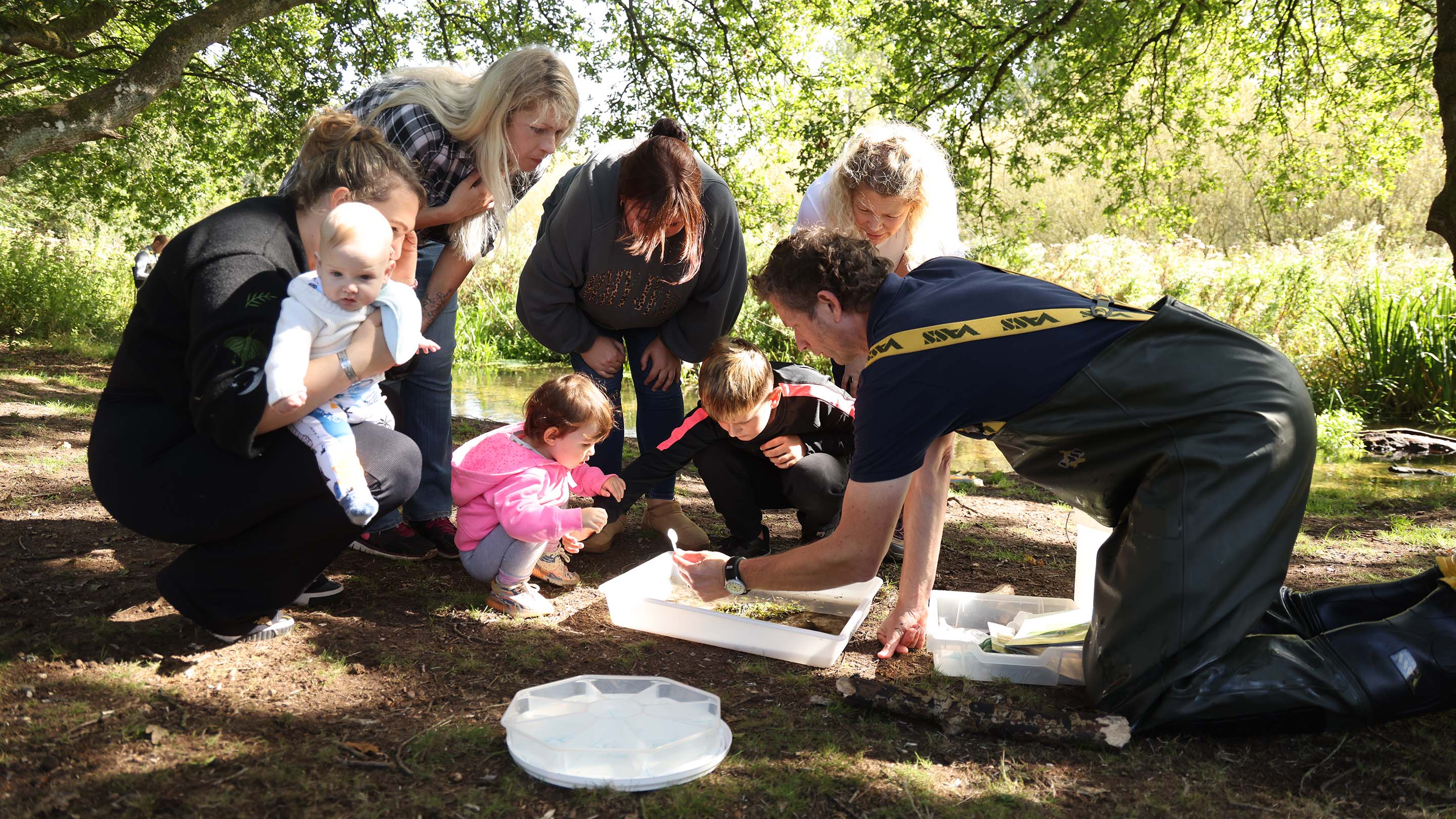 Tim Fisher, Volunteering and Engagement Lead at Norfolk Rivers Trust, shows an inquisitive group the creatures he's netted from the River Nar