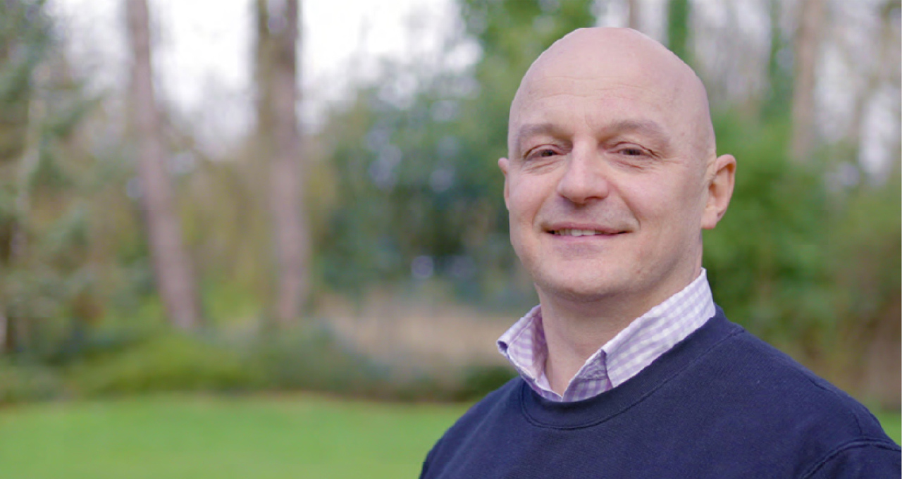 Headshot of Matt Smoth, white male, bald wearing a navy jumper with collar
