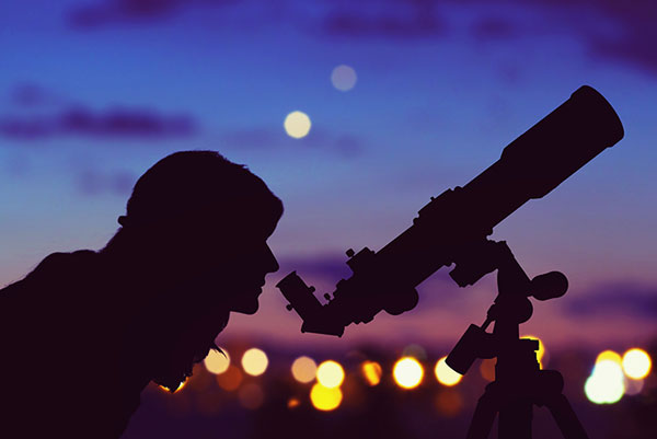 picture - a person looking out through a telescope at night