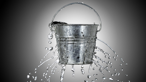 A bucket with holes and water pouring out