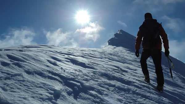 picture of a man climbing a snowy peak