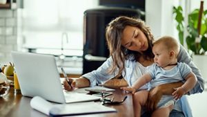 Mother holding her baby while doing her finances