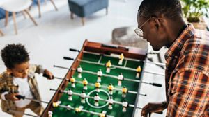 Father and son playing foosball inside