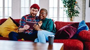 Two people sitting on sofa looking at an iPad