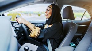 Young smiling muslim woman in traditional wear driving her car