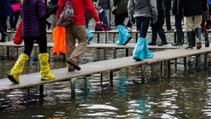 Group of people in covered shoes walking across a flooded area