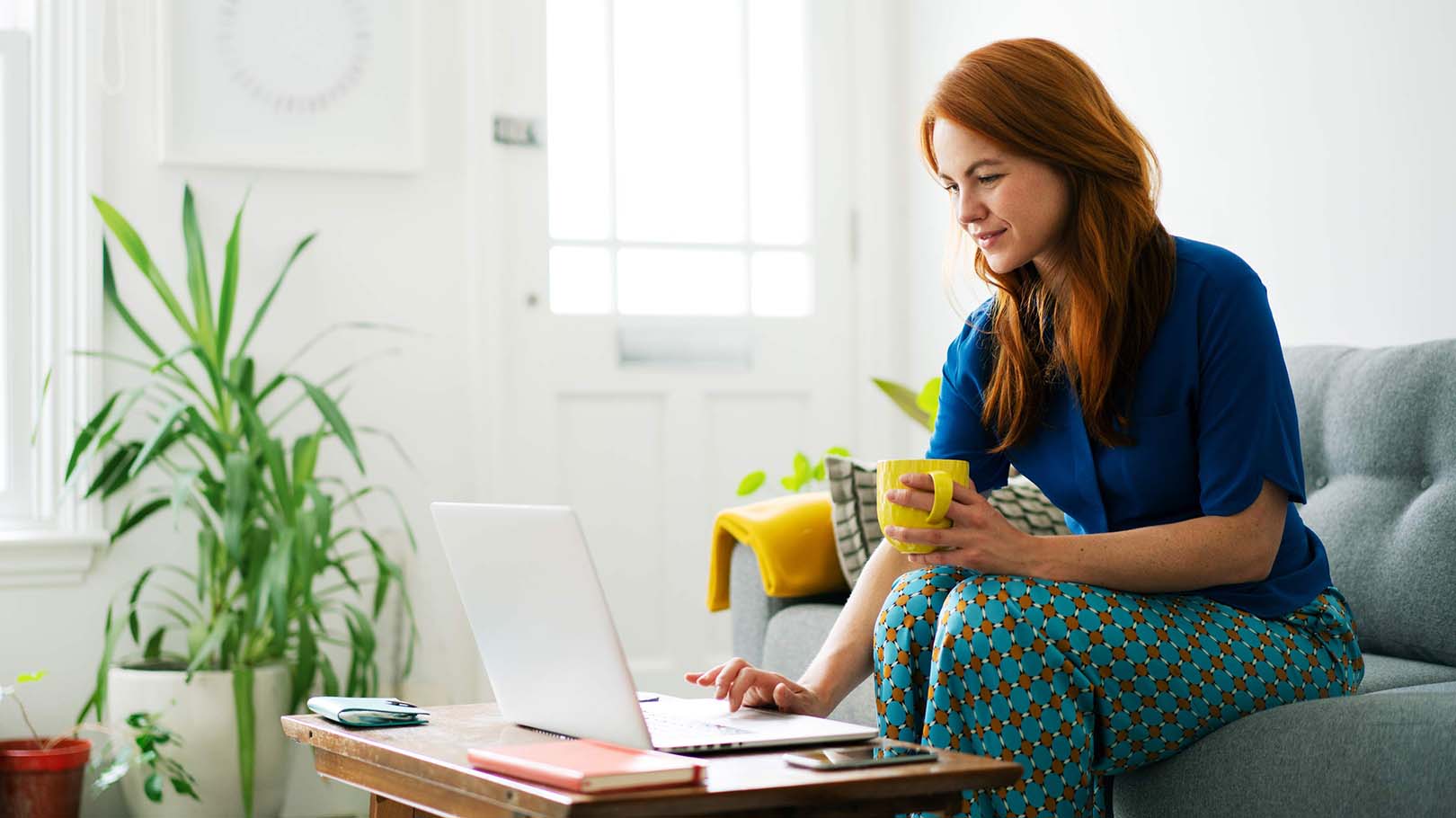 Person sat on their sofa, smiling as they get an Aviva Car Insurance quote on their laptop