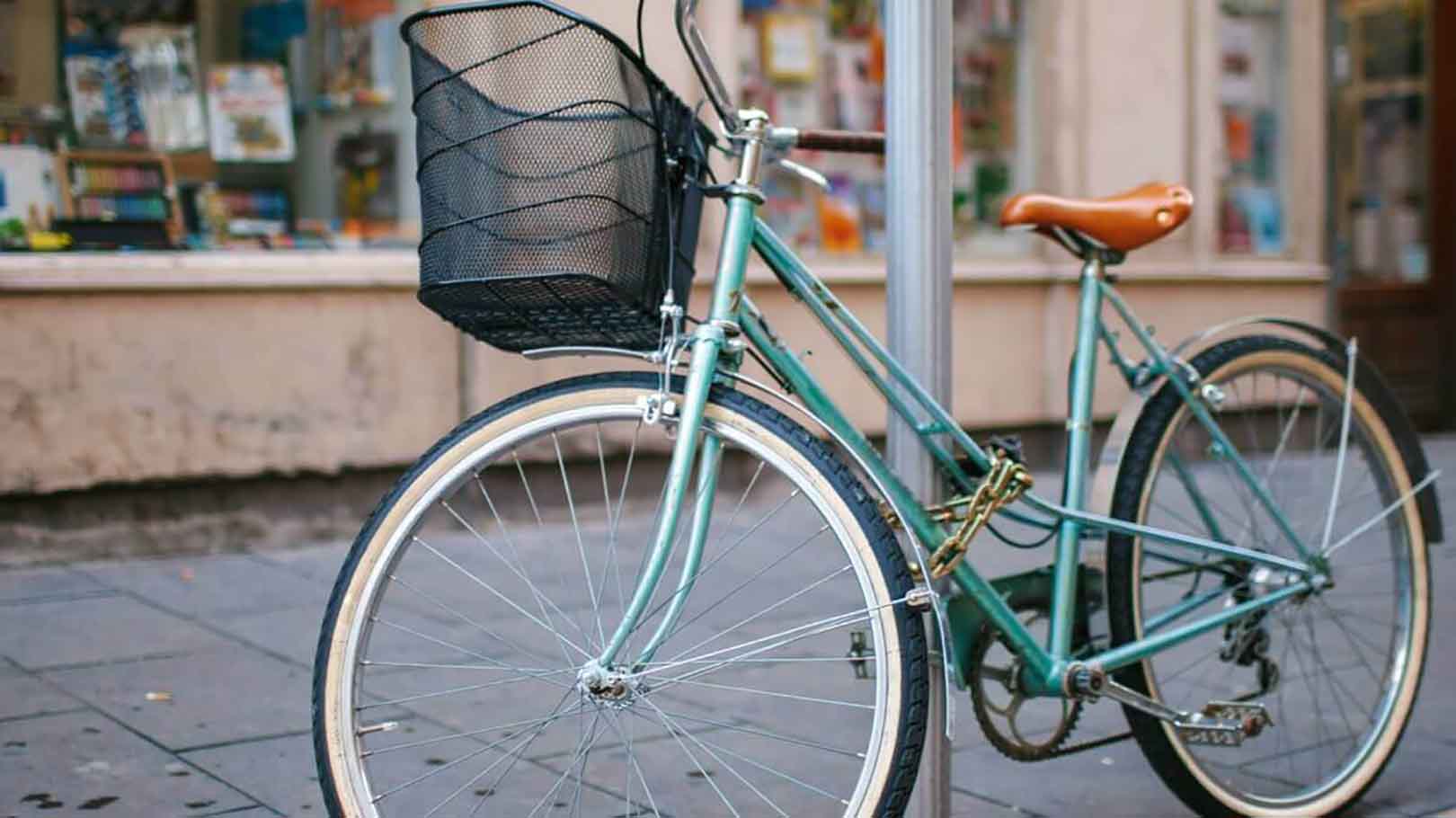 A pedal cycle (push bicycle) tied to a lamp post in a street setting