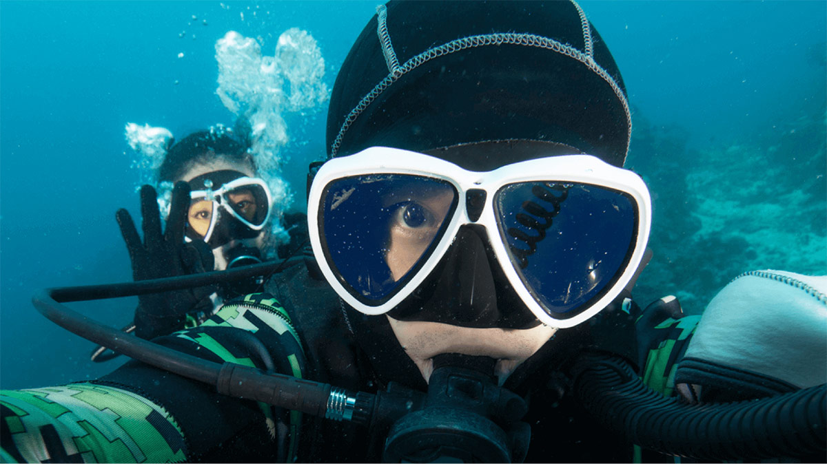 Two people posing in scuba diving gear underwater