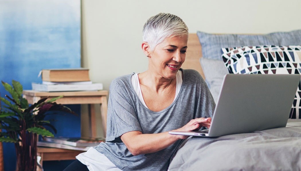 Lady smiling at laptop, while at home