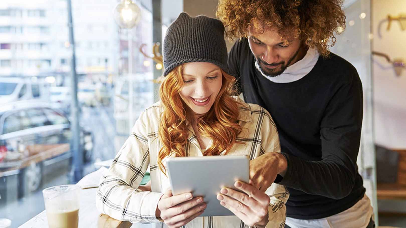 Couple in coffee shop looking at tablet