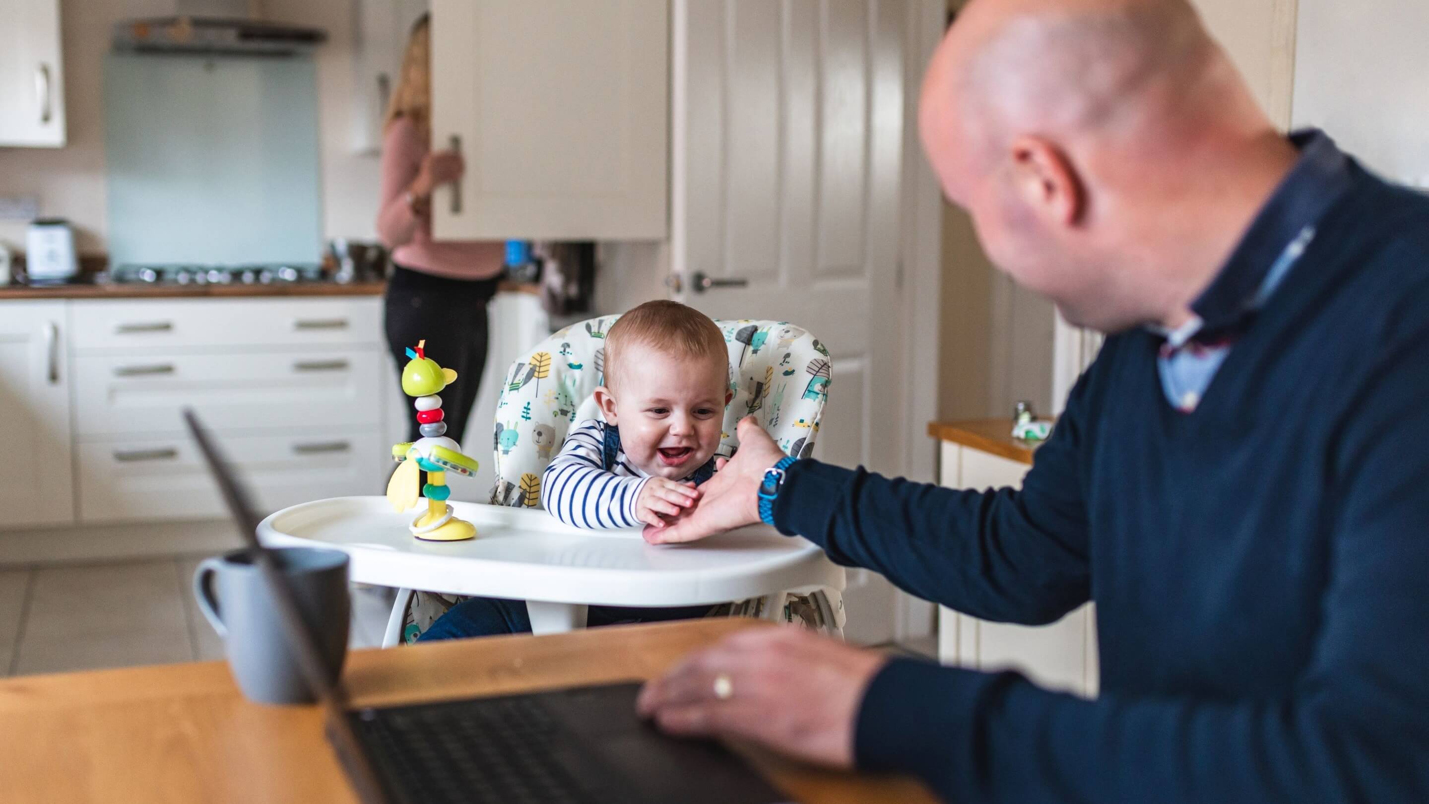 Father sitting with baby in a highchair at kitchen table