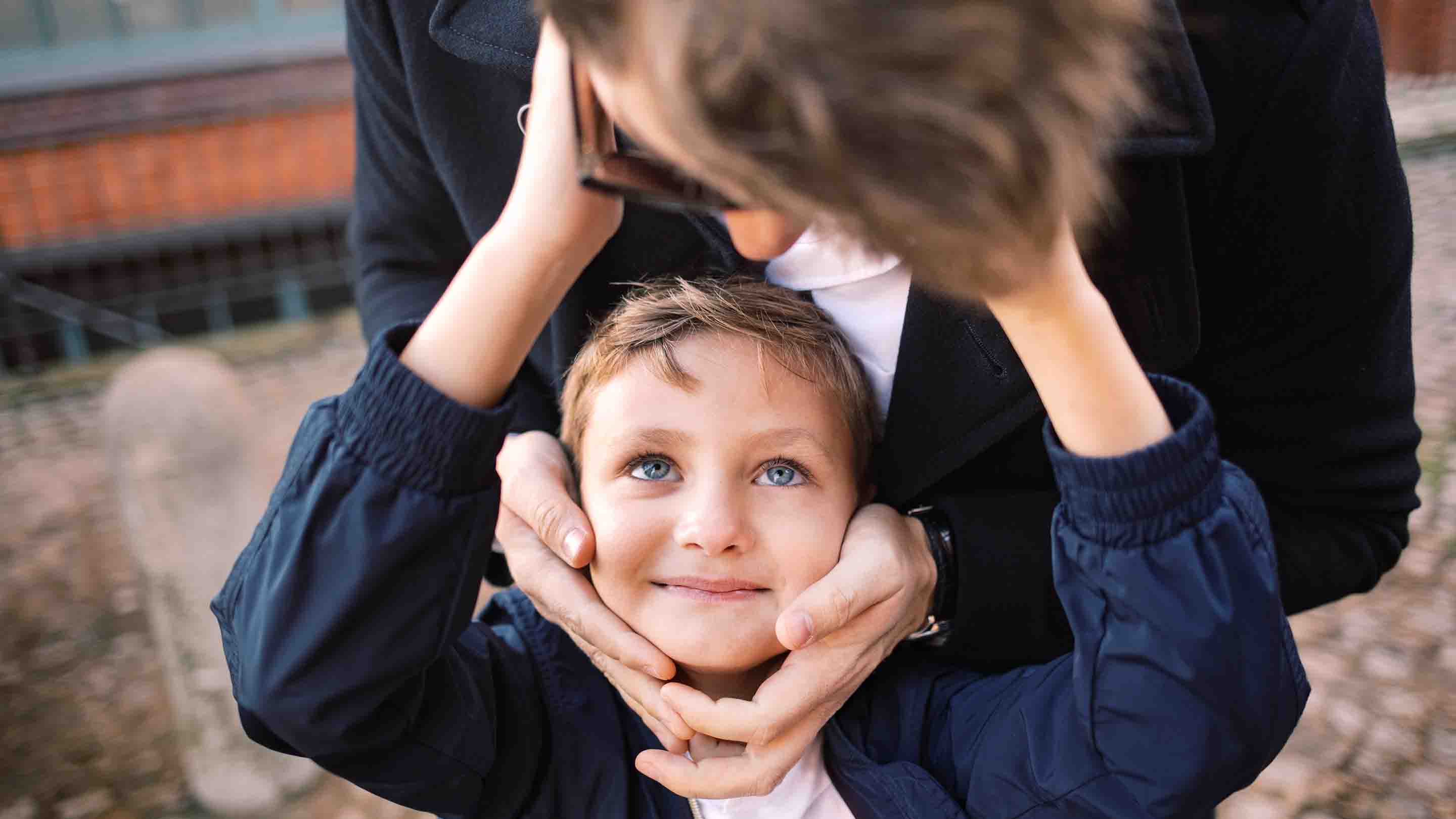 Cute blond kid holding his fathers face smiling