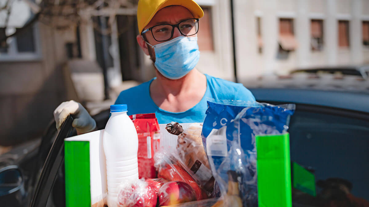 Delivery guy with protective mask and gloves delivering groceries during lock down.