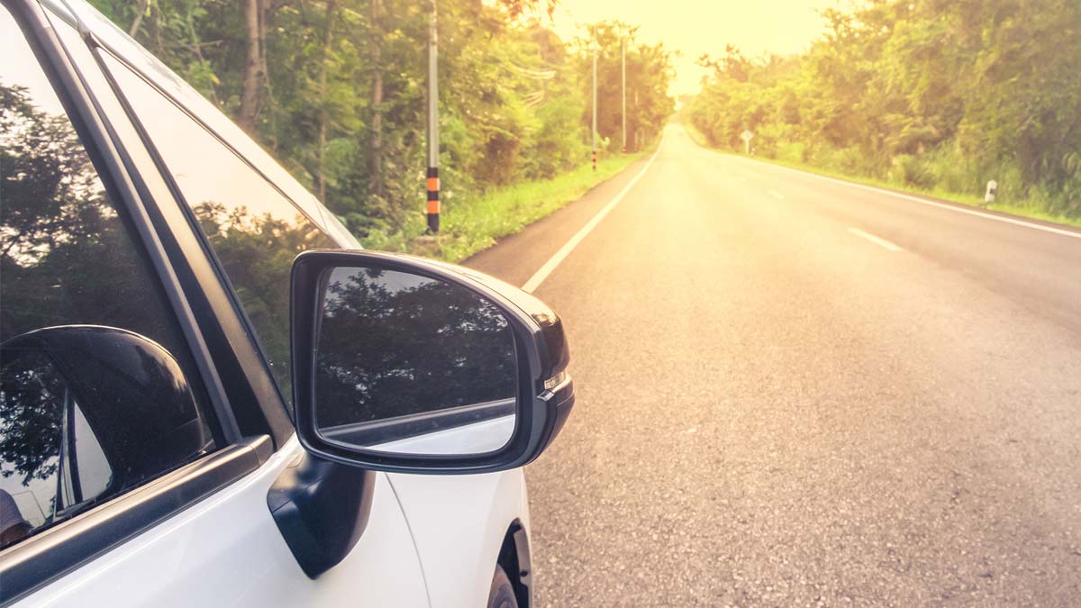 White car driving down the road on a summer’s day – keep your car protected in summer