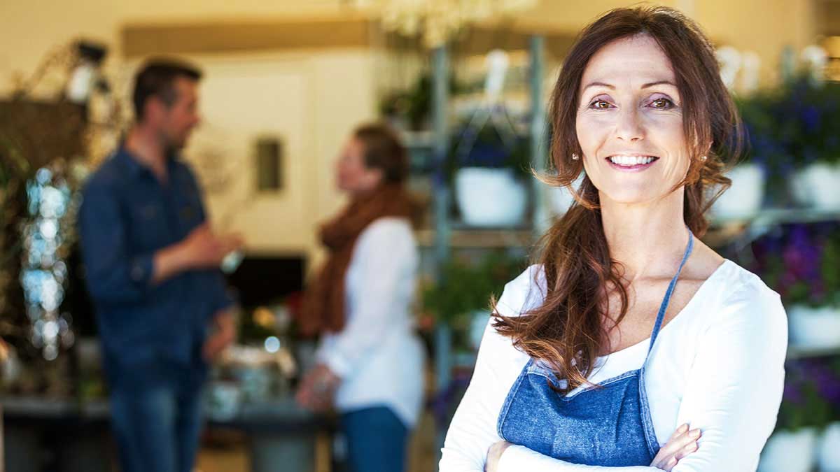 Woman smiling outside of shop ready to ask income protection questions