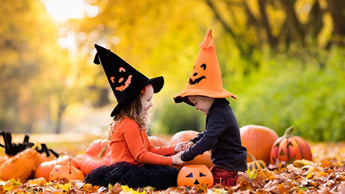 Halloween traditions - children holding hands surrounded by pumpkins