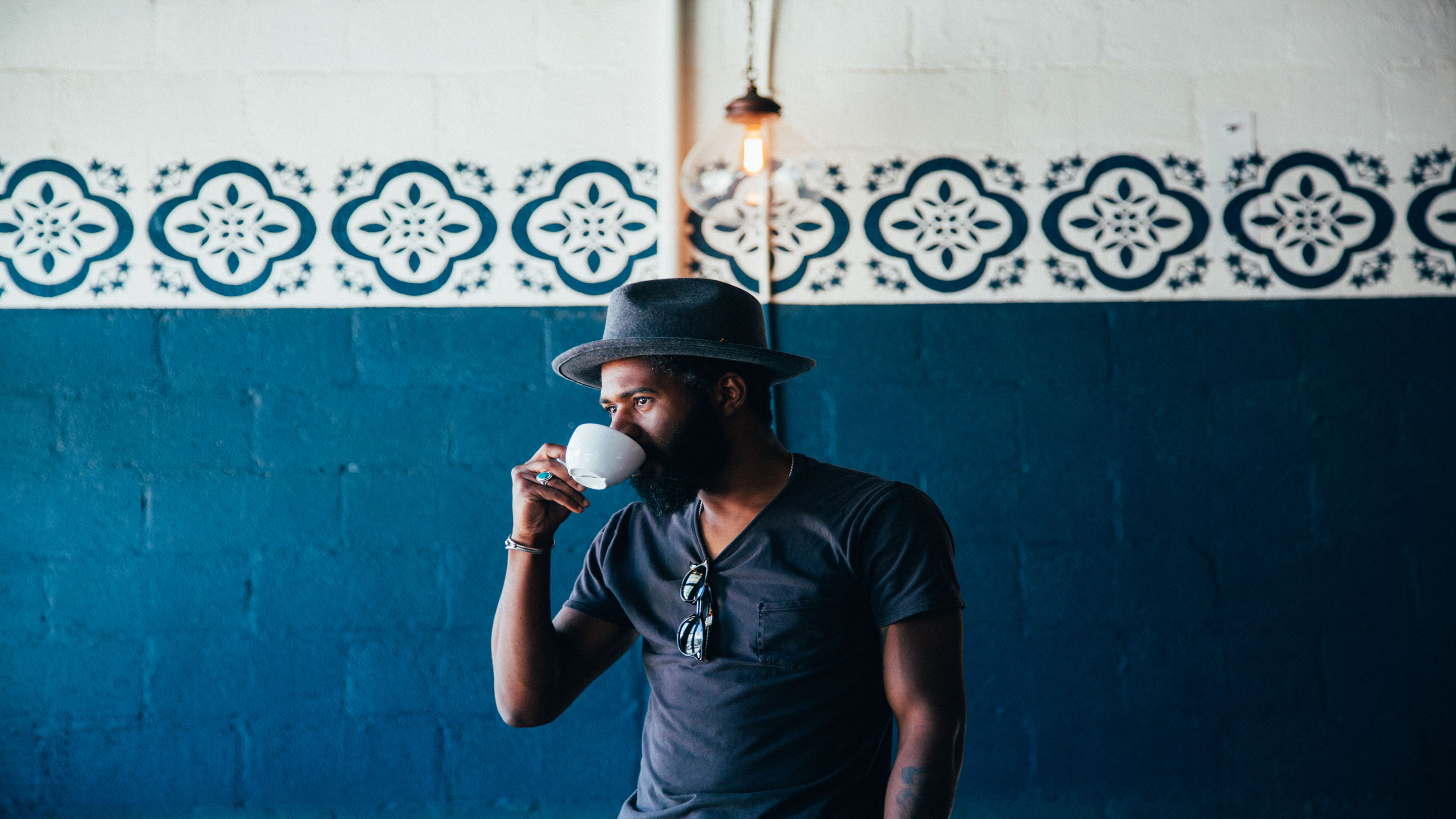 Person wearing hat and drinking from a tea cup - blue theme